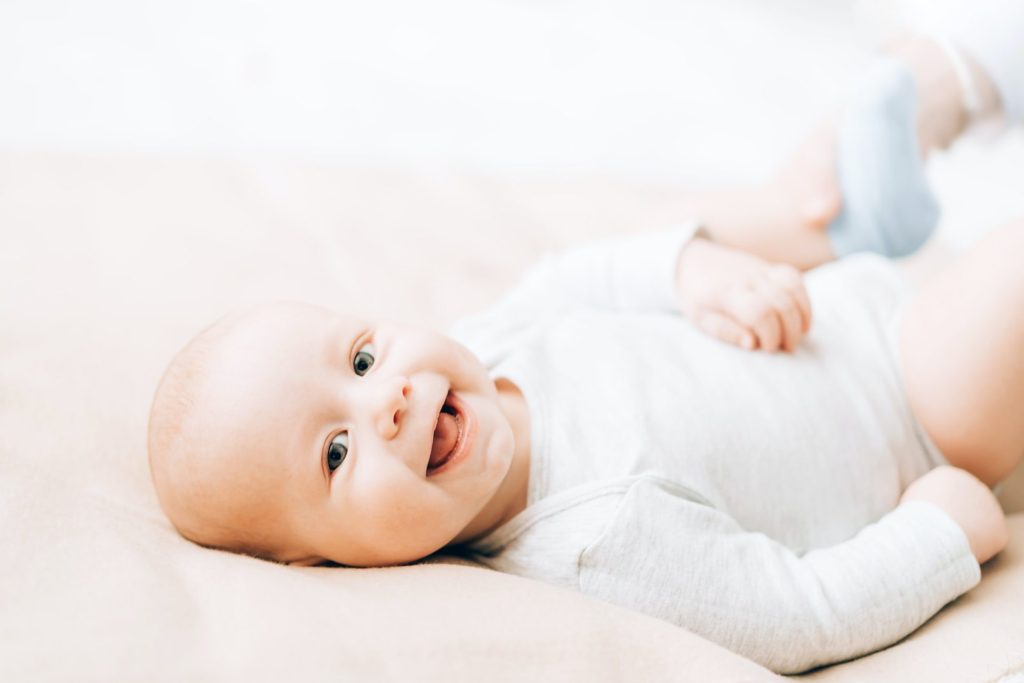newborn-laughing-baby-lying-on-the-bed-caring-for-newborn-children-e1634098456771.jpg